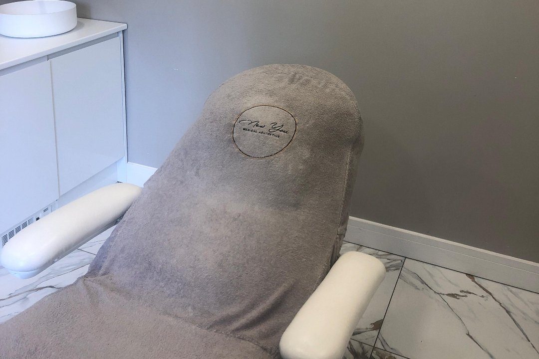 The treatment room at The NewYou Skin Clinic, with the clinic's gold ring emblem on the chair.